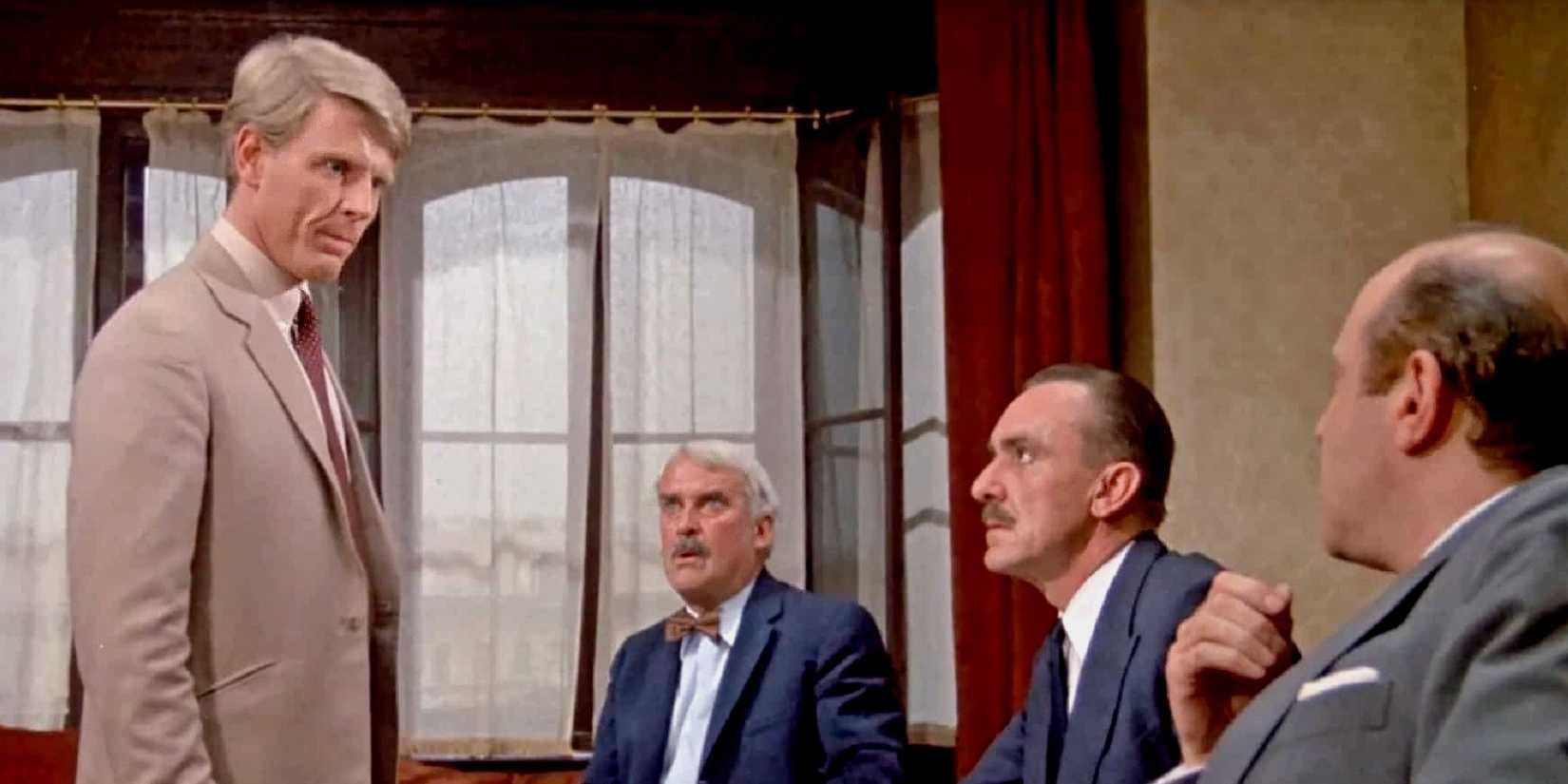 A man standing and looking down at three other men 