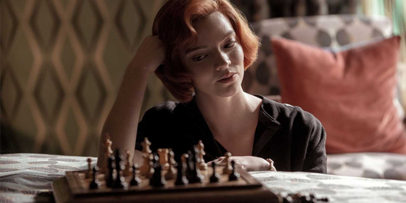 Anya Taylor-Joy sitting by the bed with a board of chess on it in The Queen's Gambit