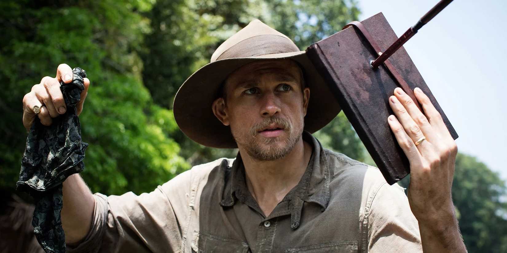 Charlie Hunnam as Percy holds up a journal to block a projectile in The Lost City of Z.