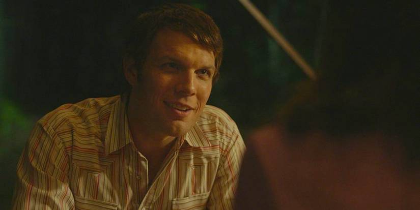 Jake Lacy talks to someone at night in A Friend of the Family.