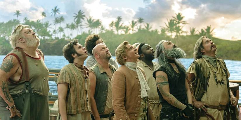 The pirate crew of the Revenge from Our Flag Means Death stands on the deck of the ship, looking upward