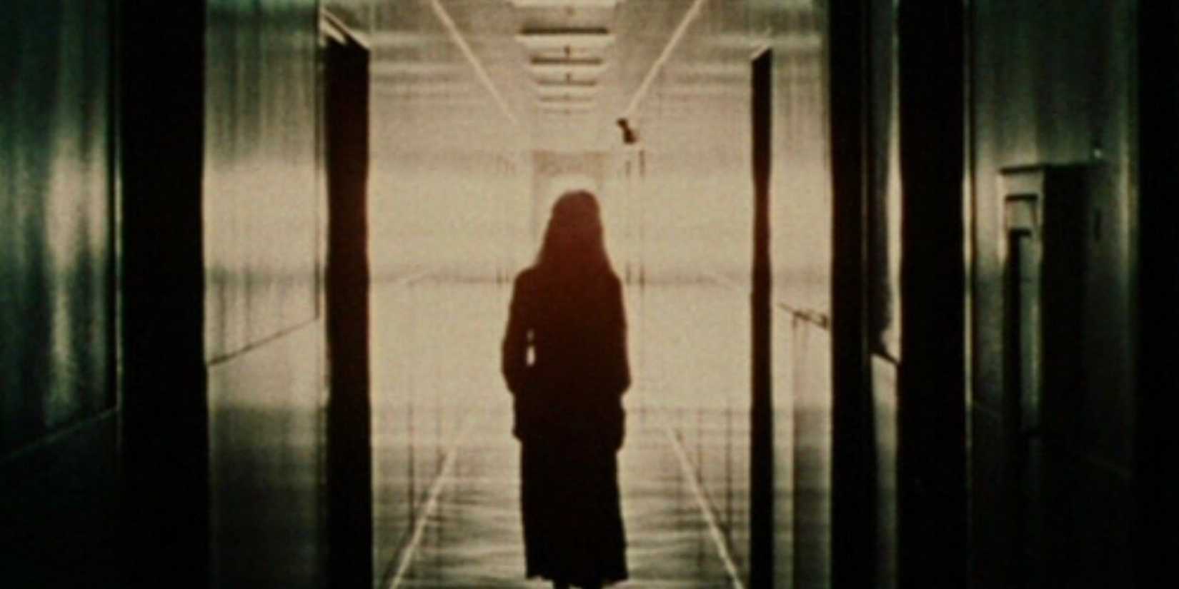 A silhouette of Arletty (Marianna Hill), backlit by white light, walks down a long hallway.