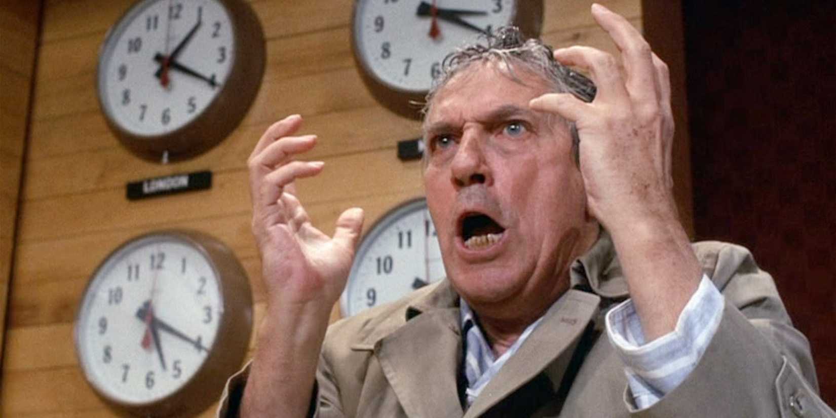 Peter Finch is a sweaty man in front of clocks, shouting with his hands up in Network