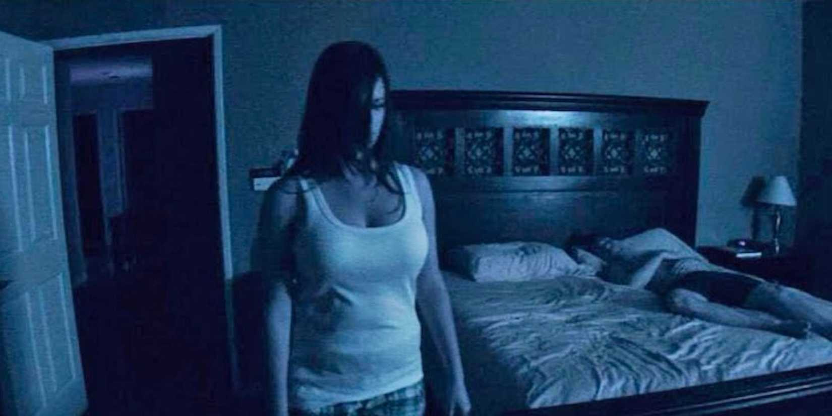 Katie Featherston as Katie creepily stands by the bed with Micah Sloat as Micah in Paranormal Activity