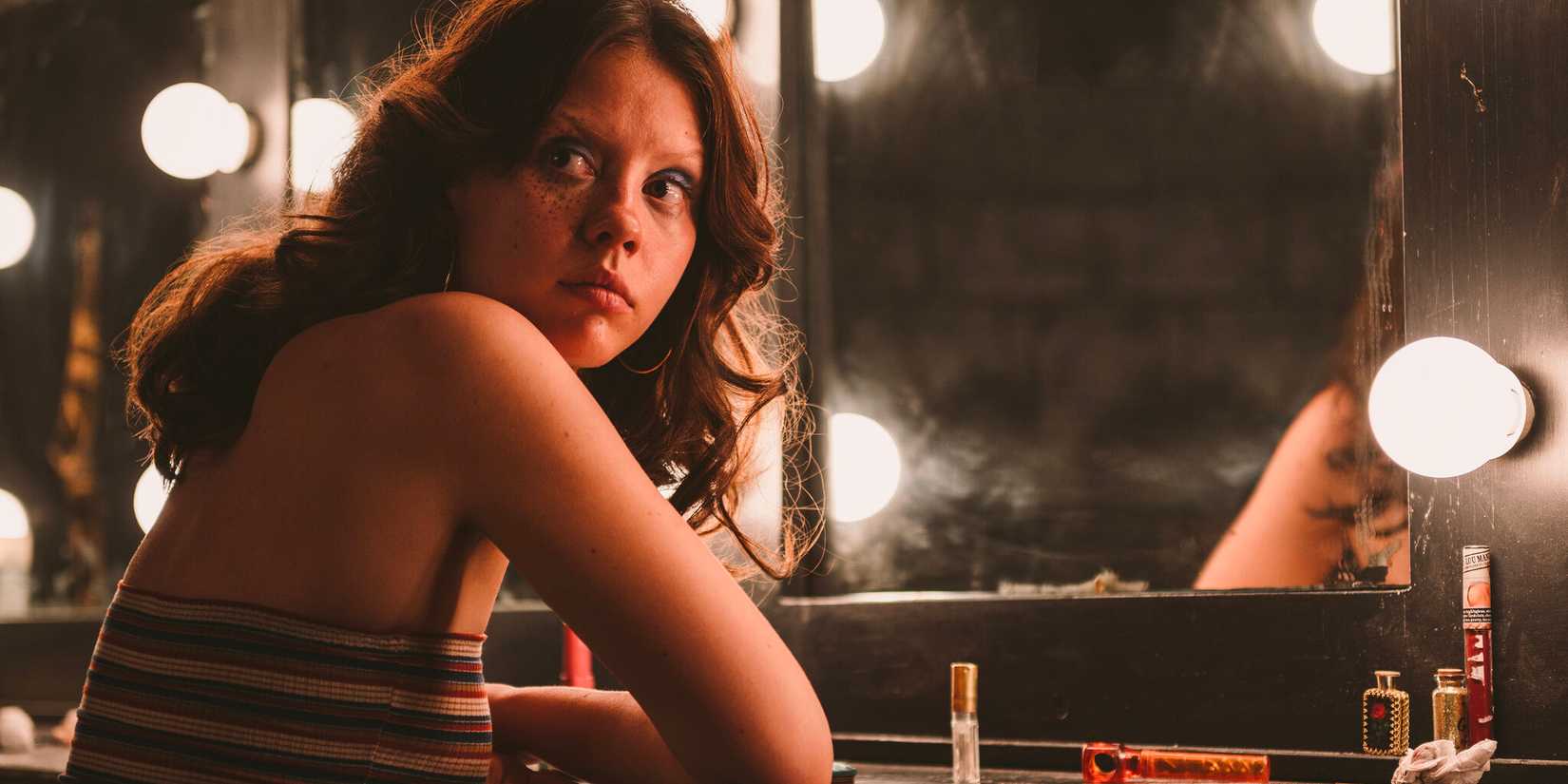 13 filmes para assistir em uma Sexta-Feira 13 12 Maxine sentada em frente ao espelho do seu camarim, olhando para trás em 'X' (2022).