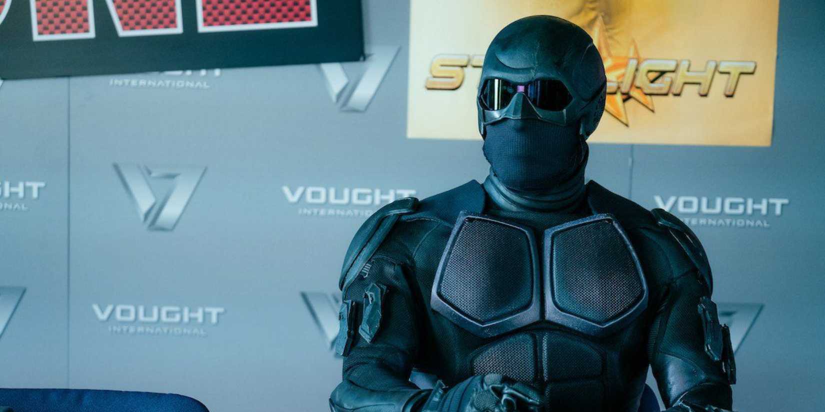 Black Noir sitting in front of Vought promotions in The Boys