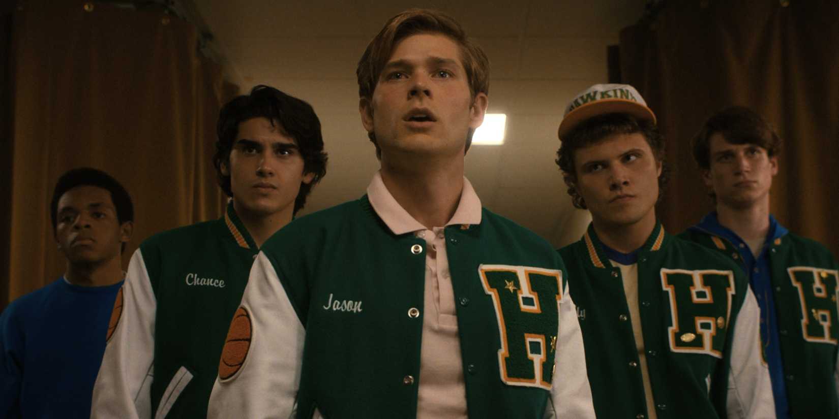 Mason Dye as Jason Carver in a letter jacket with others behind in Stranger Things.