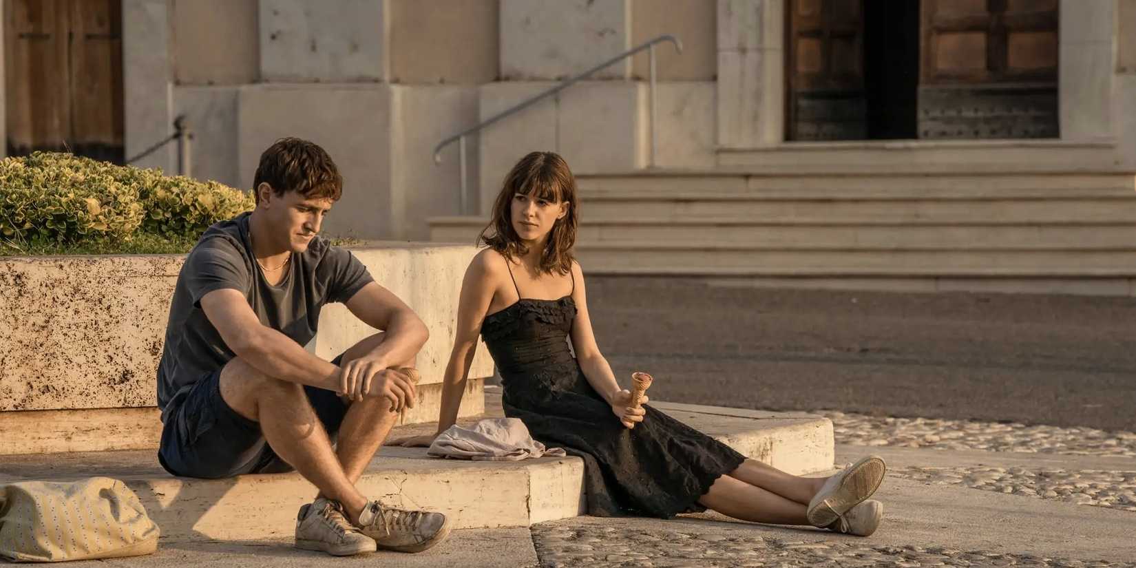 Daisy Edgar-Jones as Marianne and Paul Mescal as Connell sit on stone steps outside in Normal People.