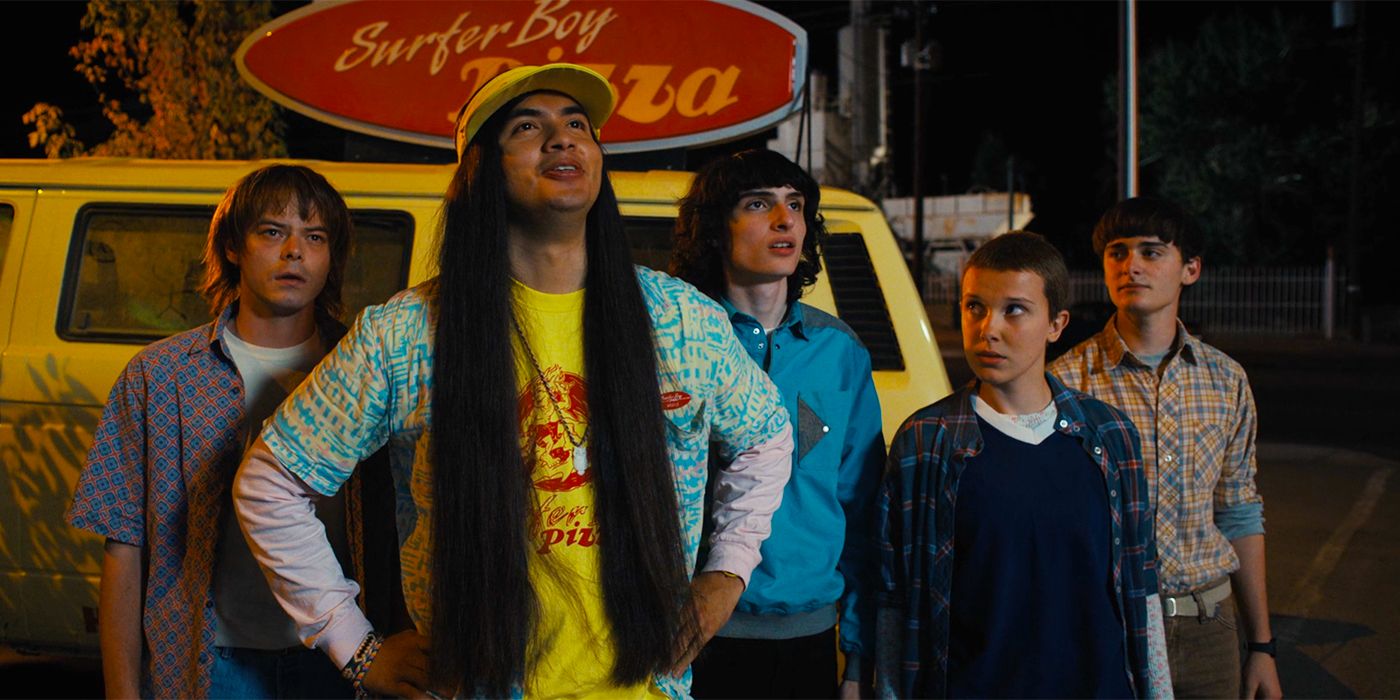 a group of people standing in front of a pizza van in the dark