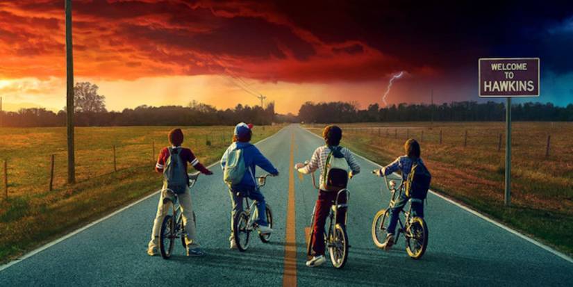 Mike, Will, Dustin, and Lucas on bikes looking at an ominous cloud over Hawkins in Stranger Things.