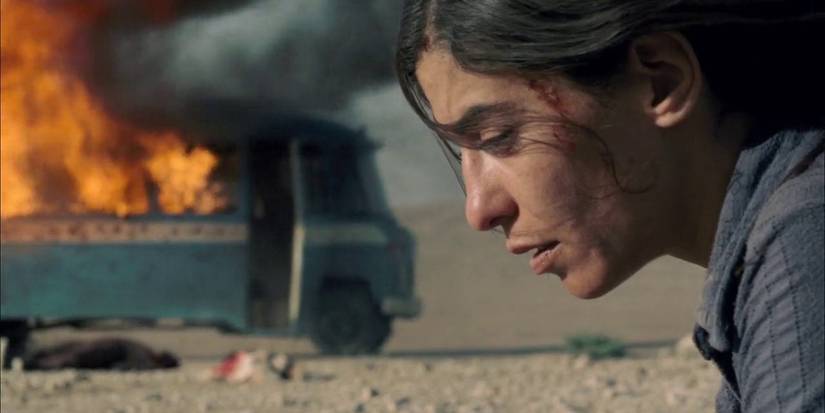 Lubna Azabal as Nawal Marwan looks distraught in front of a burning wreckage in Incendies.