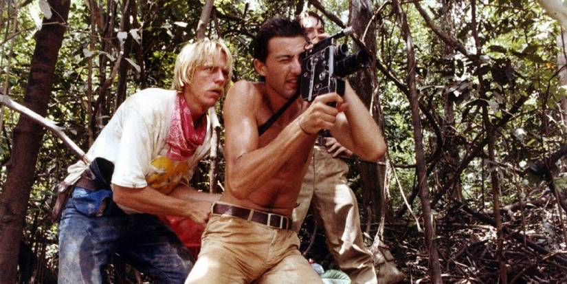 Luca Barbareschi dan Perry Pirkanen sebagai Mark Tomaso dan Jack Anders, berdiri di hutan dan merekam dengan kamera video di Cannibal Holocaust