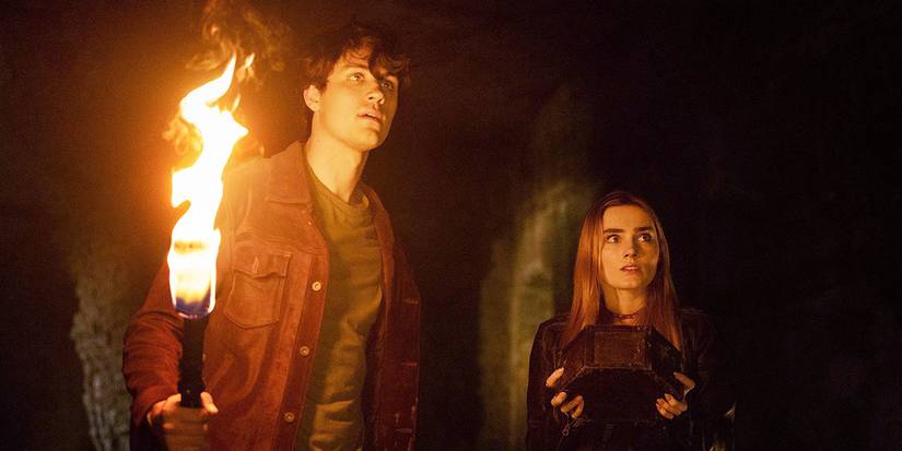 Drake Rodger and Meg Donnelly as John and Mary Winchester, holding a torch and looking frightened on The Winchesters
