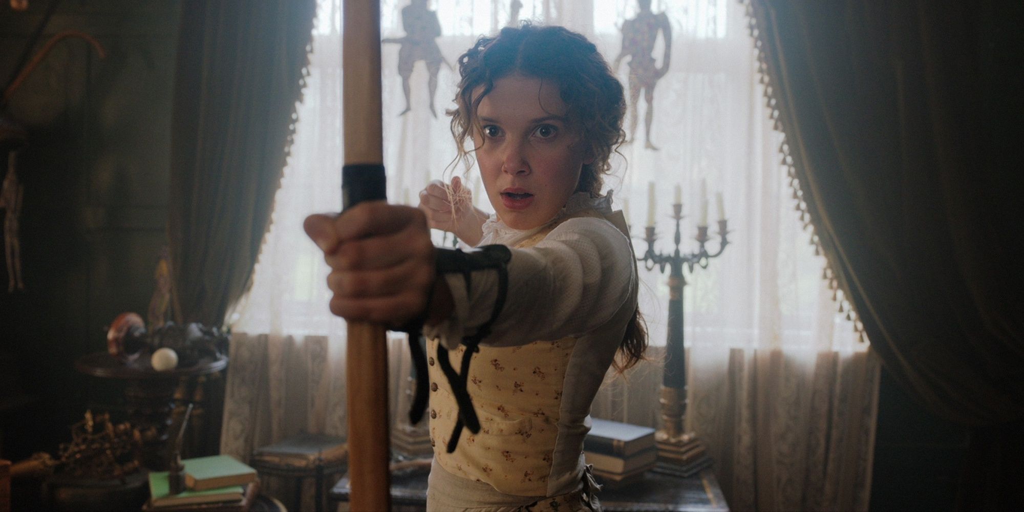 Enola Holmes with a bow and arrow in 'Enola Holmes 2.'