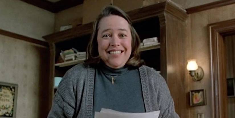 Annie Wilkes (Kathy Bates) holding a transcript with a desperate smile in Misery