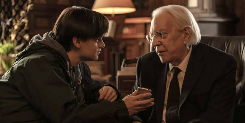 Jaeden Martell holds an iPhone out as Donald Sutherland grimaces in Mr. Harrigan's Phone.