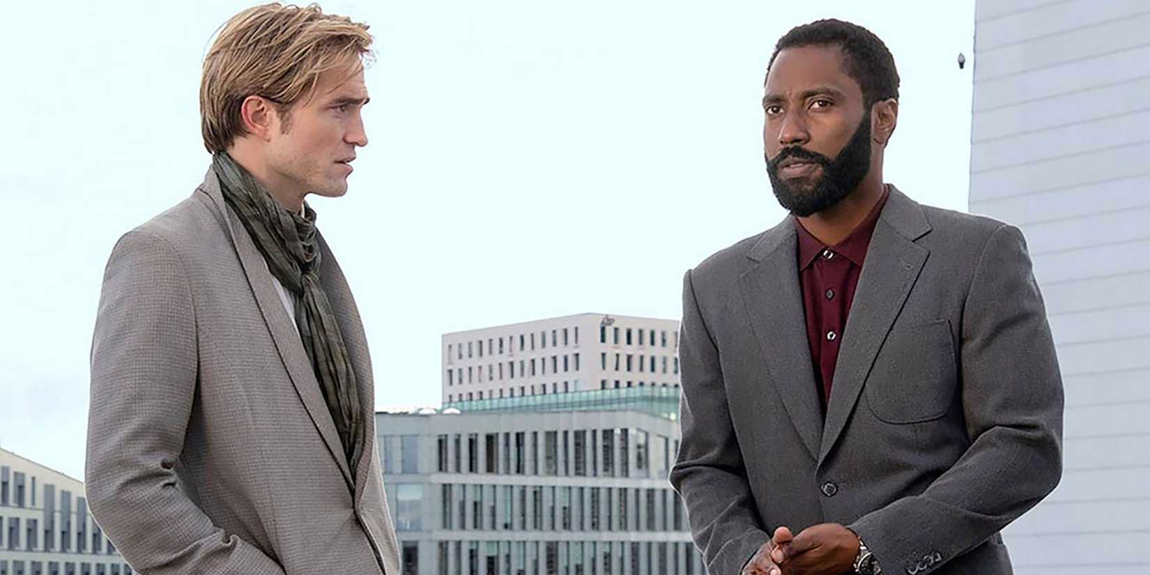 Robert Pattinson (left) and John David Washington stand and talk on a skyscraper balcony in Tenet