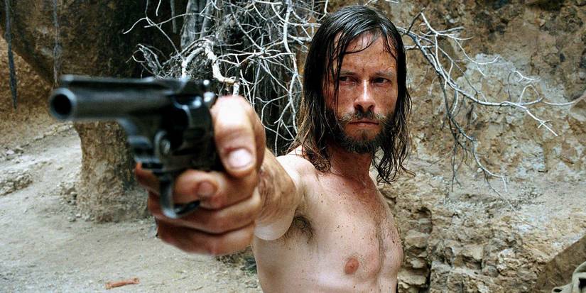 Charlie Burns aiming a gun at someone off-camera in The Proposition