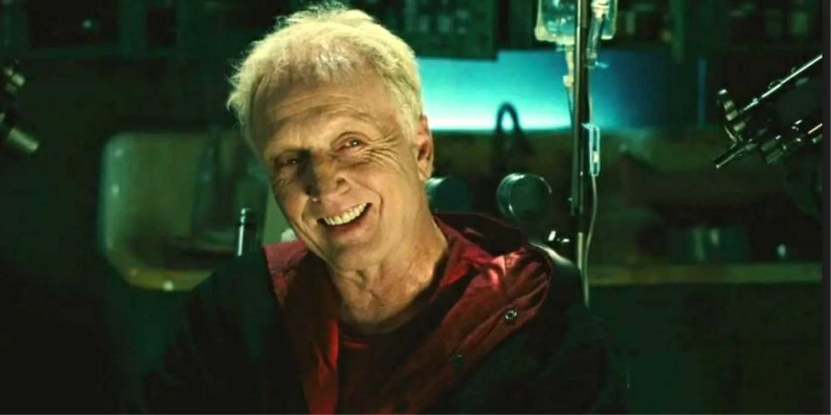 John Kramer, played by actor Tobin Bell, sat in his workshop grinning in Saw II.