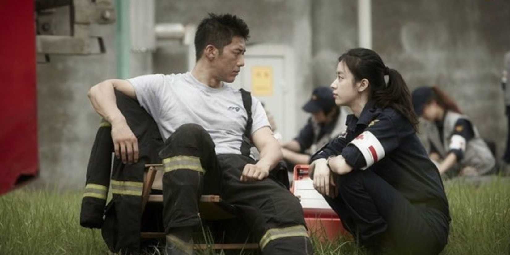 a firefighter and a paramedic sitting side by side on the ground