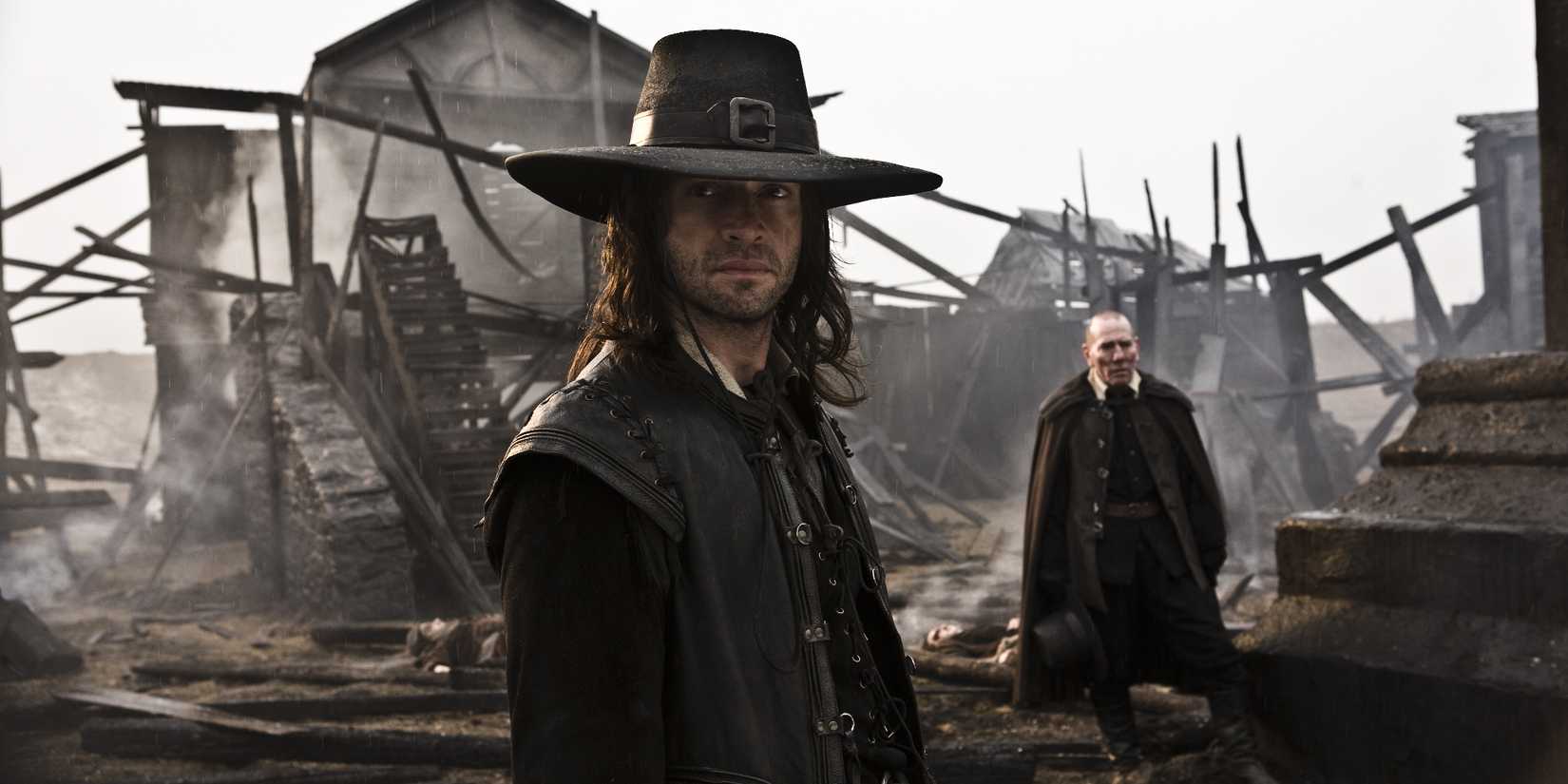 Solomon Kane (James Purefoy), a man in all black clothes and a black hat, stands amid the smuldering ruins of a village in medieval times.