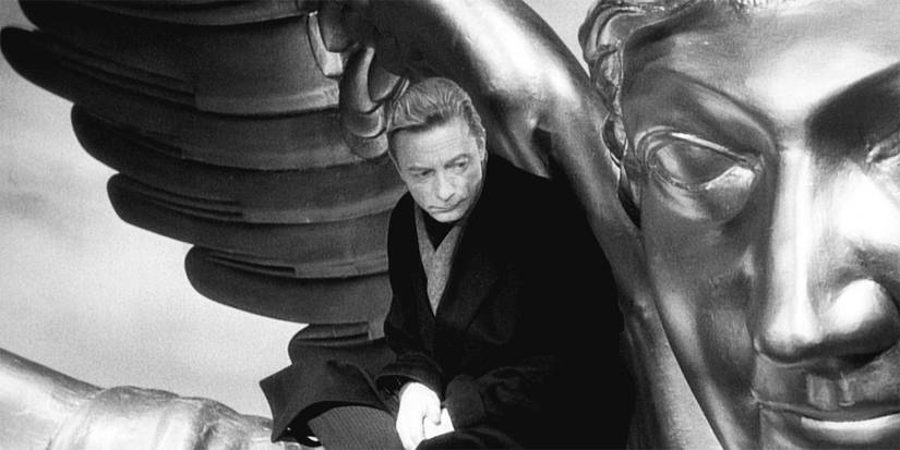 A man under the wings of an angel statue in wings-of-desire