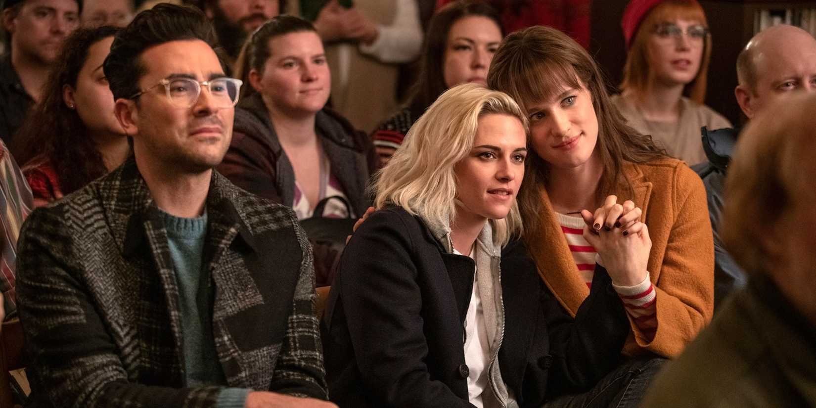 Kristen Stewart as Abby and Mackenzie Davis as Harper hold hands at a performance in Happiest Season.