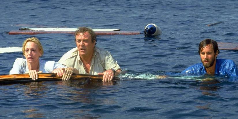 Lorraine Gary, Michael Caine and Lance Guest holding onto detritis in the water in Jaws: The Revenge