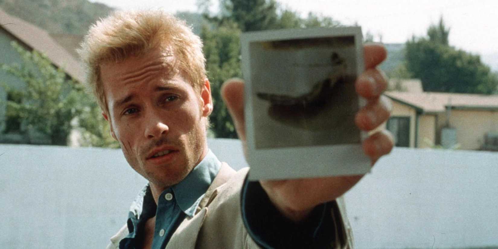 Guy Pearce as Leonard Shelby showing a polaroid to someone off-camera in Memento.