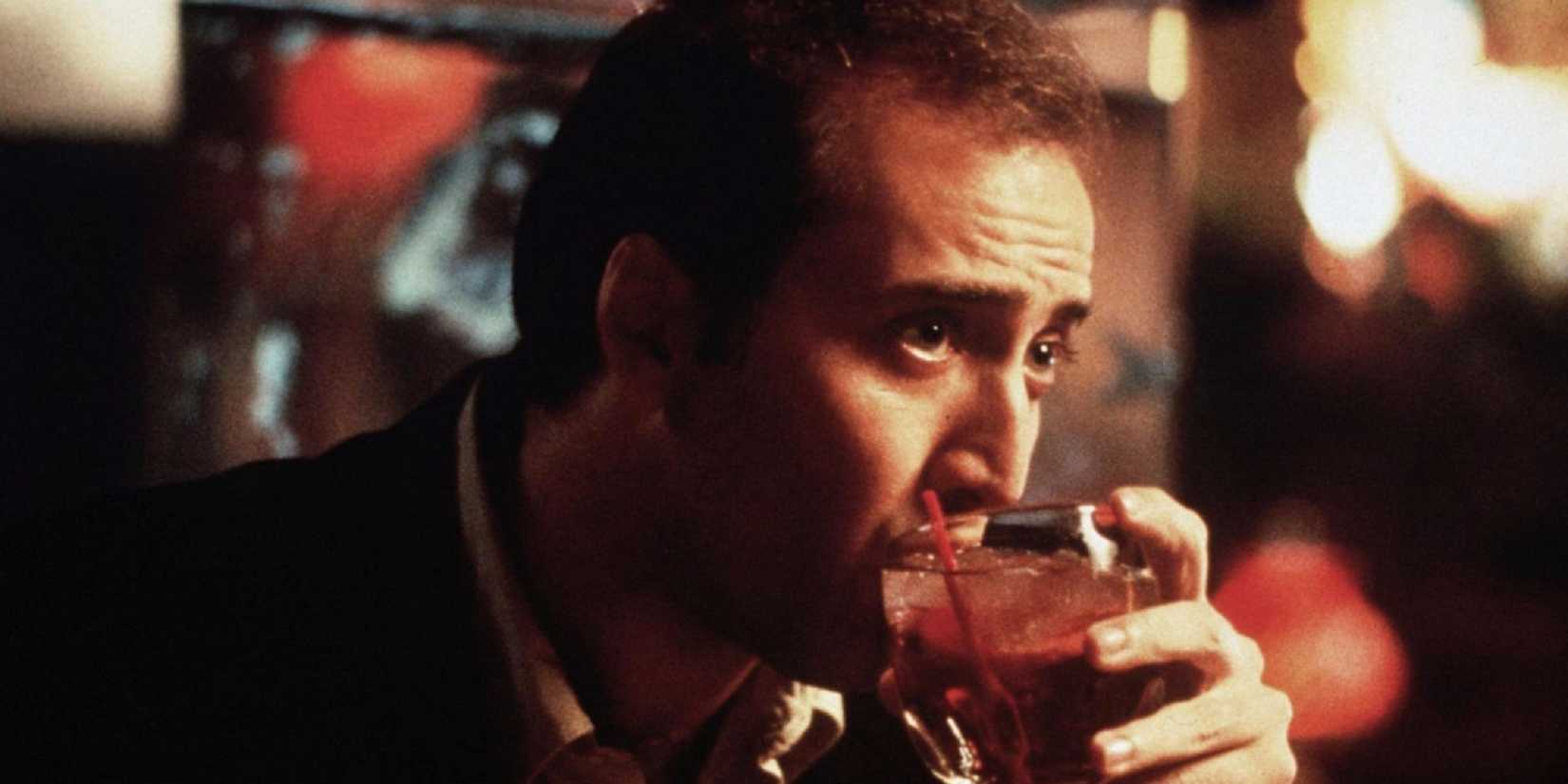 Nicolas Cage drinking a cocktail in a blurred casino in 'Leaving Las Vegas.'