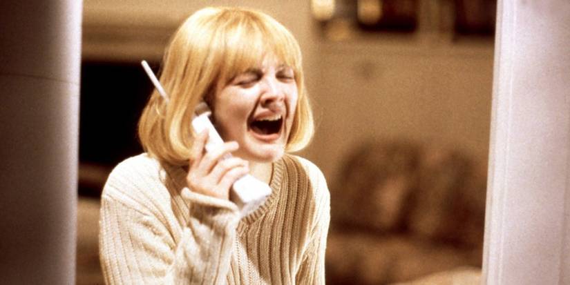 Drew Barrymore as Casey wearing a beige sweater and holding a phone while crying in Scream