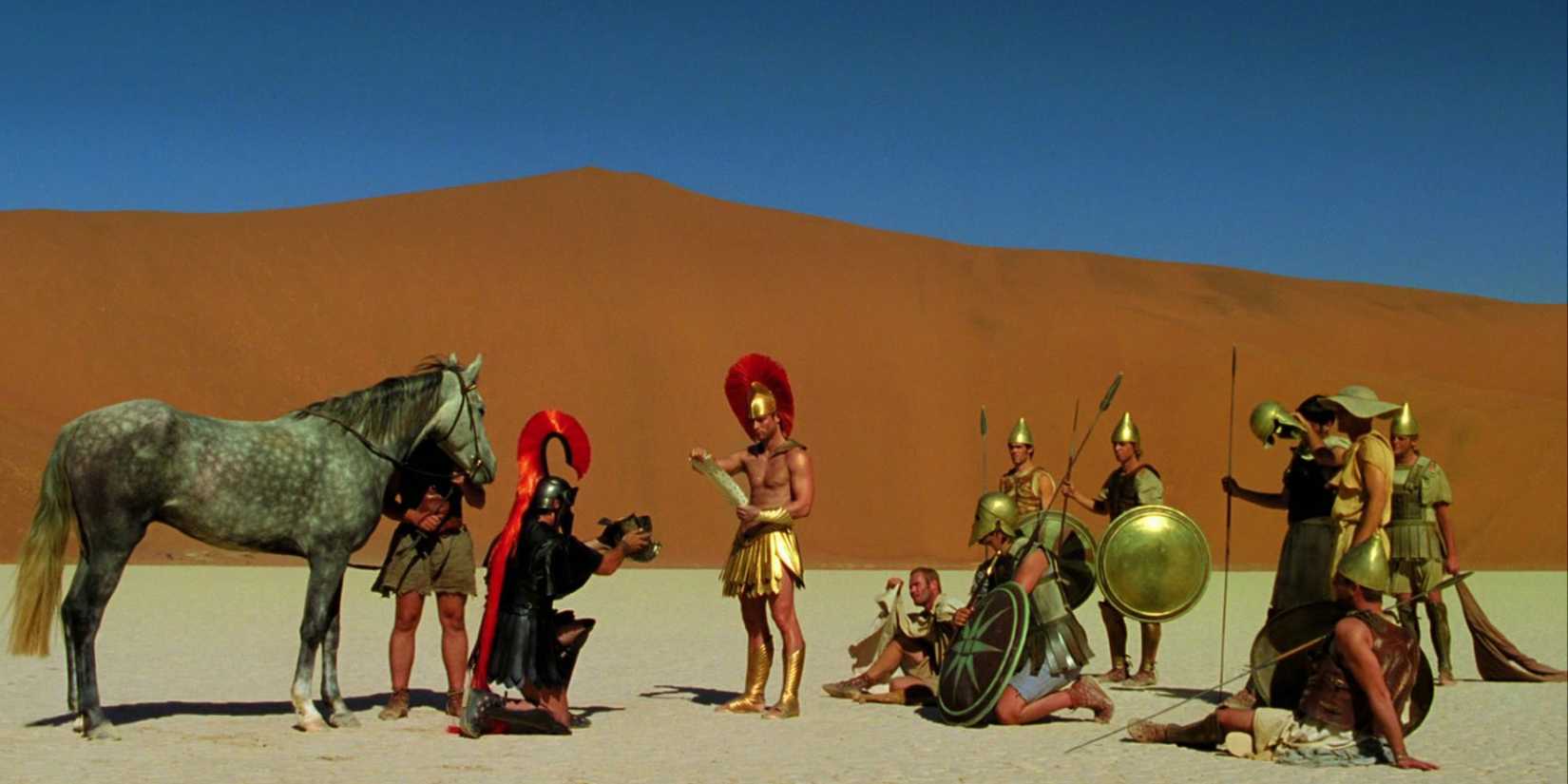 Alexander the Great (Kim Uylenbroek) reads a message among a crew of soldiers and a horse in a desert in 'The Fall' (2006)
