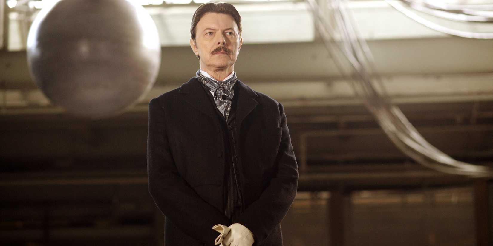 David Bowie as Nikola Tesla wearing a suit & standing stoically in The Prestige (2006)