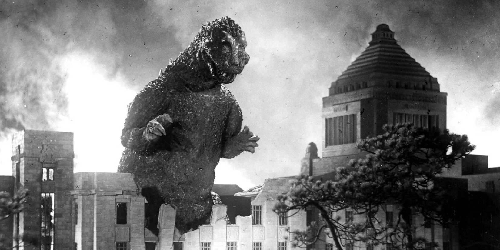Godzilla towering over a populated area on a smoky night