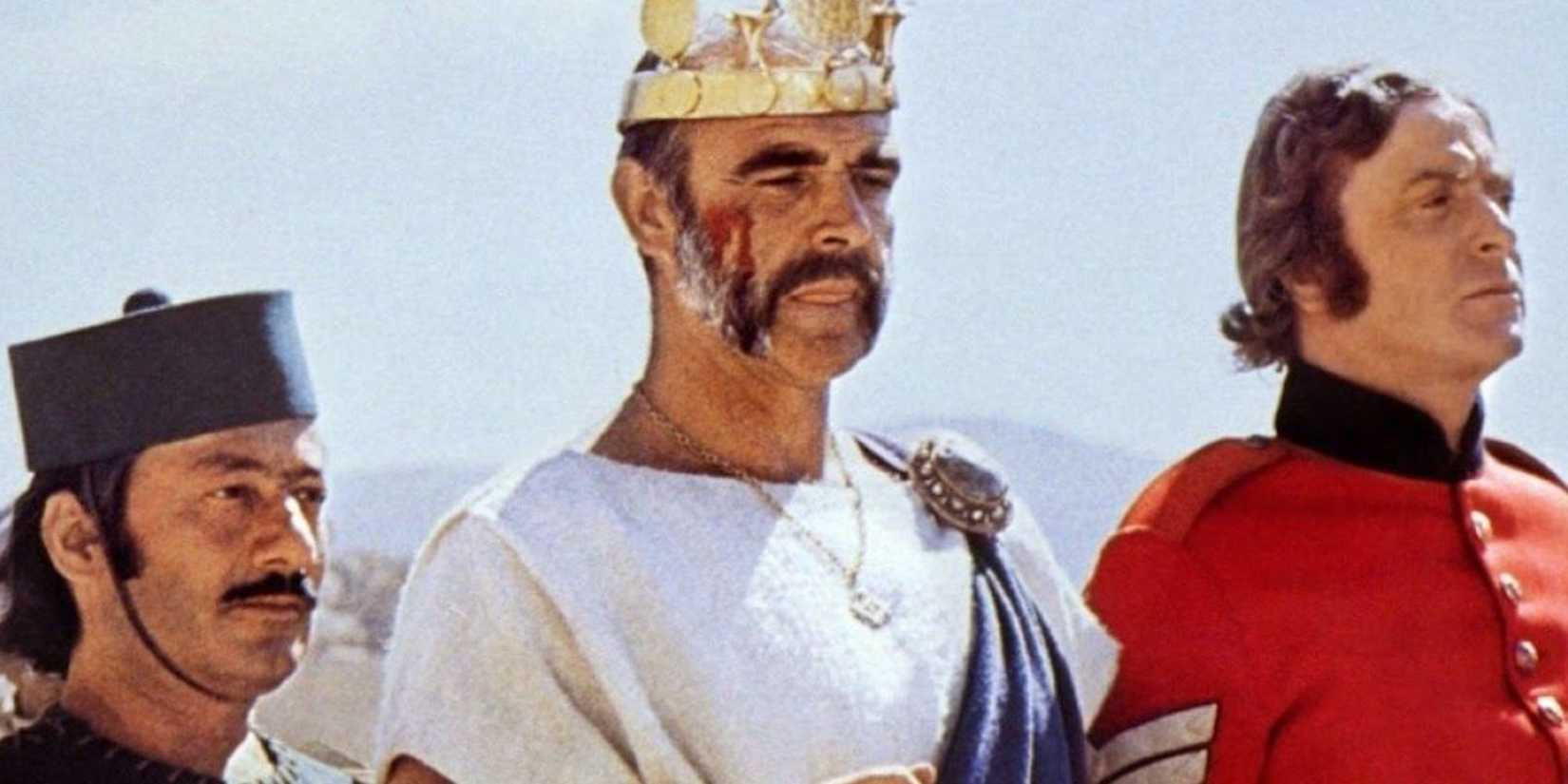 Sena Connery wearing a crown and looking ahead with Michael Caine beside him in The Man Who Would Be King