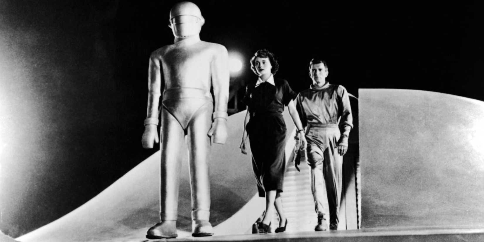 Gort and Klaatu walking out of a spaceship with a woman in The Day the Earth Stood Still