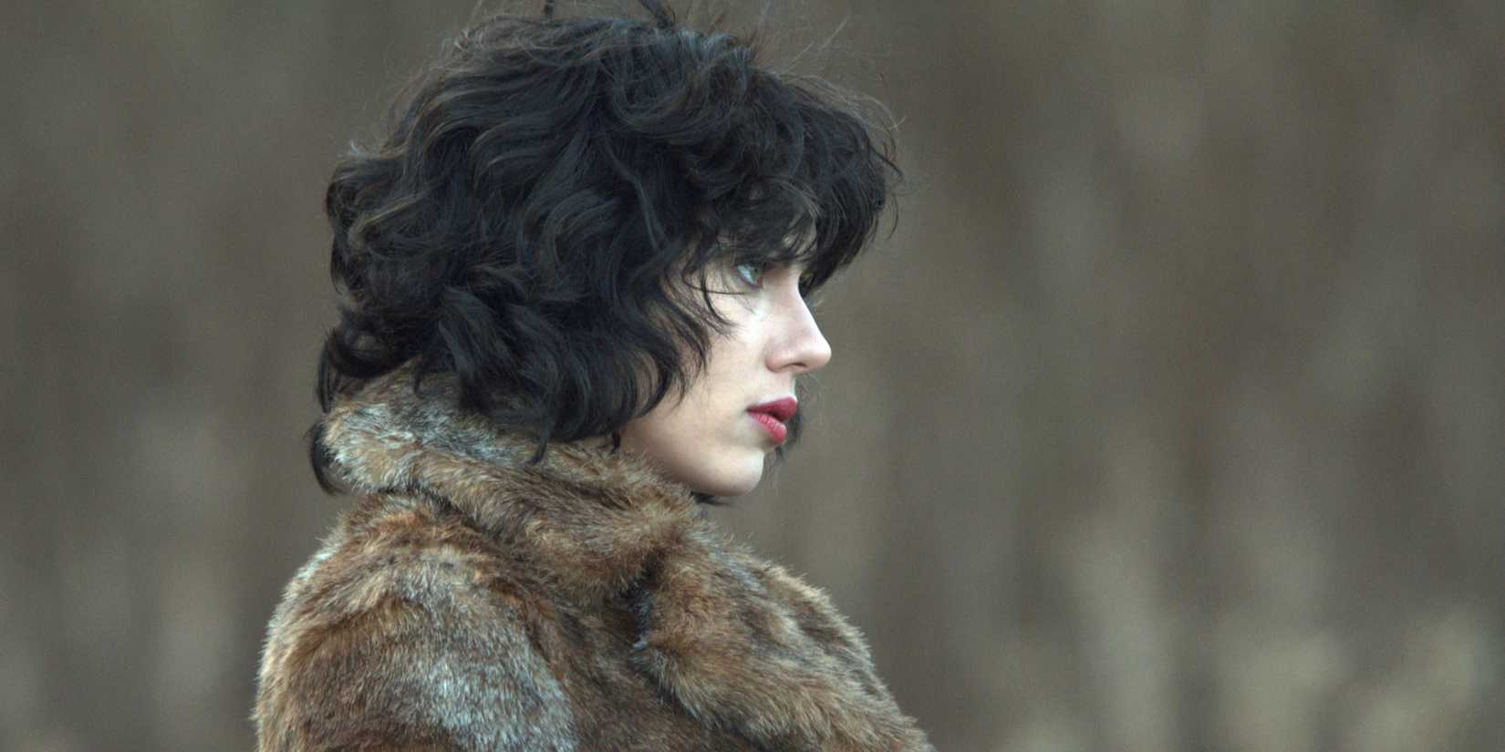 The woman faces to the right, wearing a fur coat in Under the Skin