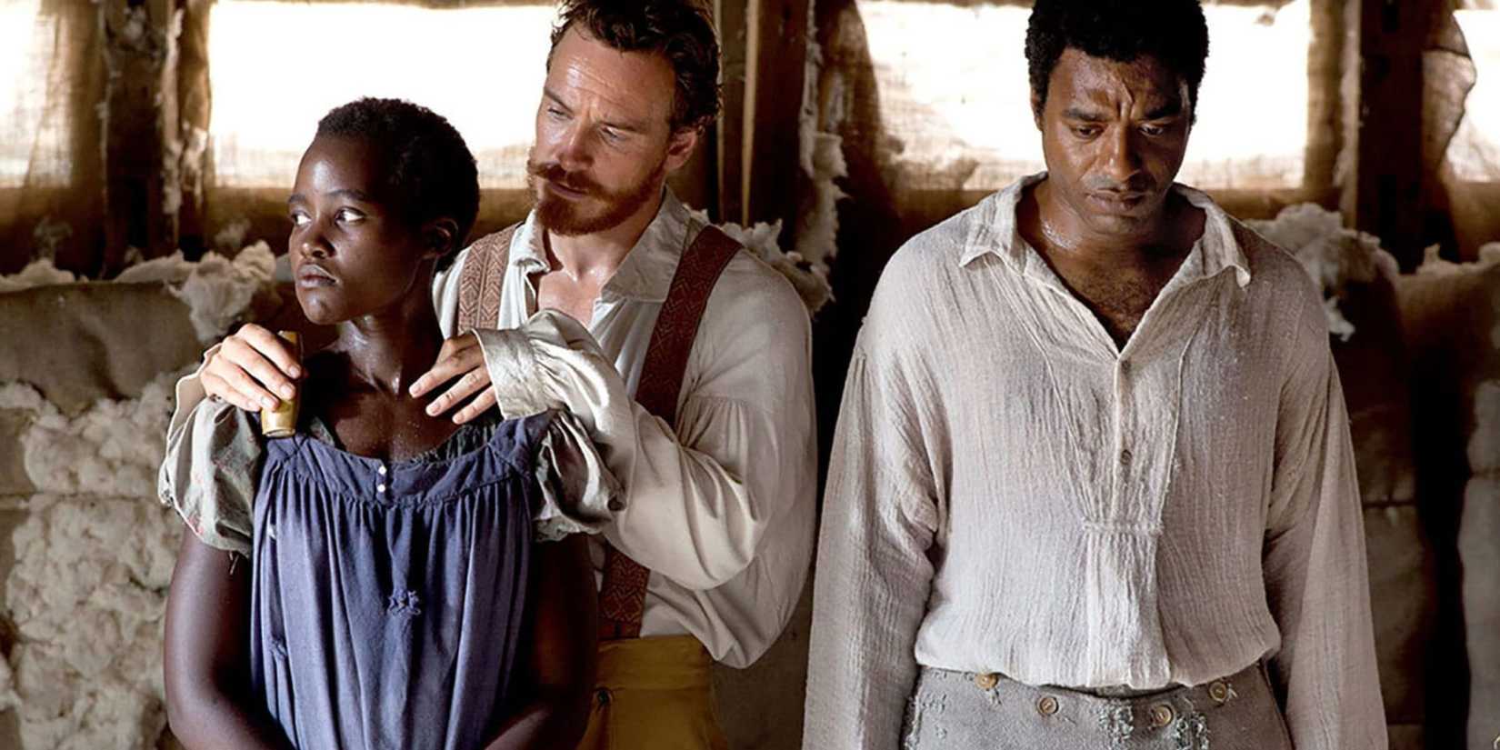Michael Fassbender with his hands on Lupita Nyong'o's shoulders while Chiwetel Ejofor stands quietly in 12 Years A Slave