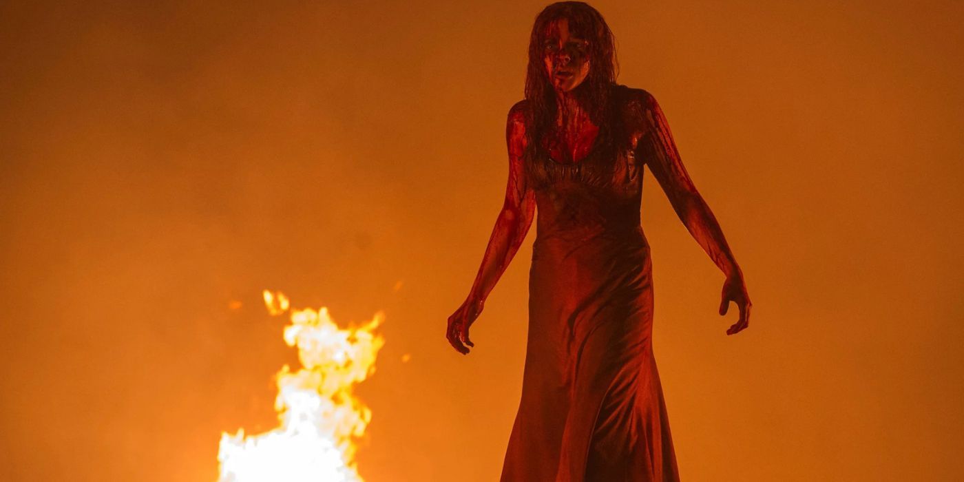 Chloe Grace Moretz como Carrie, coberta de sangue e diante do fogo no remake de Carrie de 2013