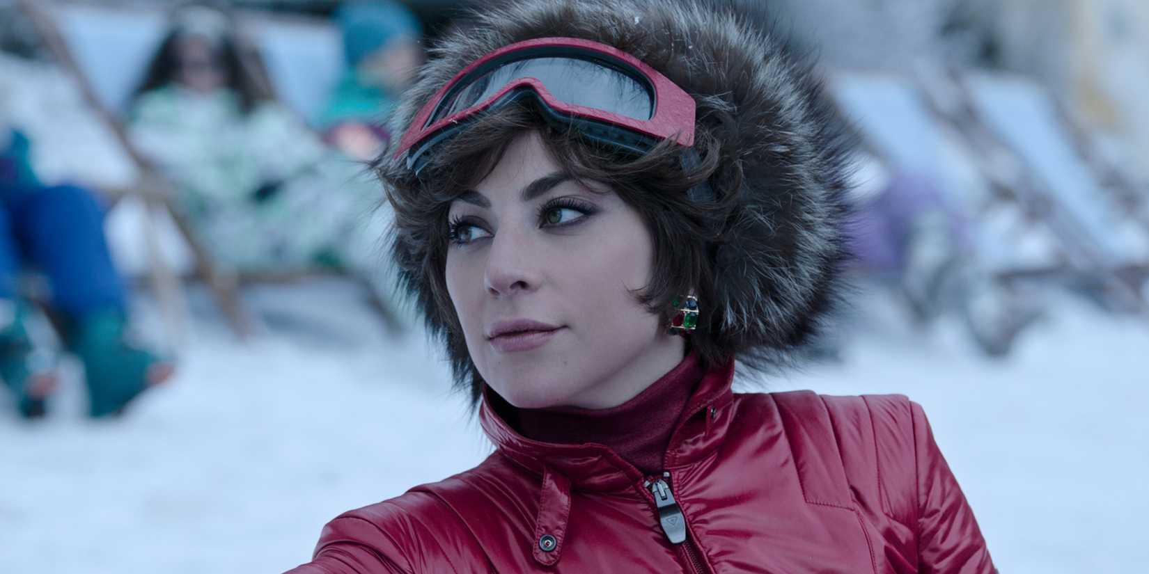 Lady Gaga as Patrizia Reggiani standing in the snow in ski gear and smiling in House of Gucci