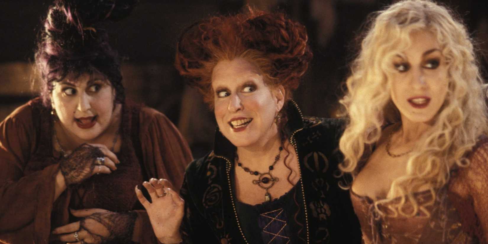 Kathy Najimy, Bette Midler and Sarah Jessica Parker as the Sanderson Sisters look sideways in Hocus Pocus.