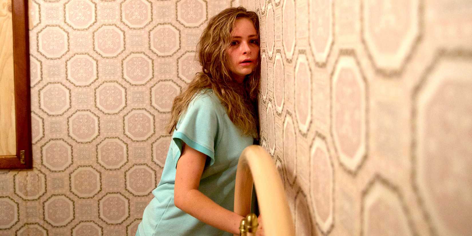 A teenage girl chained to a bed with her head pressed against the wall in Hounds of Love