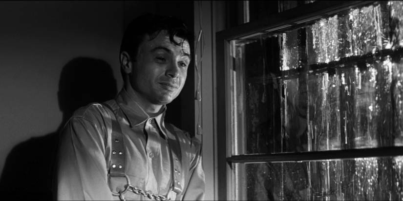 A man standing by a window as it rains in In Cold Blood