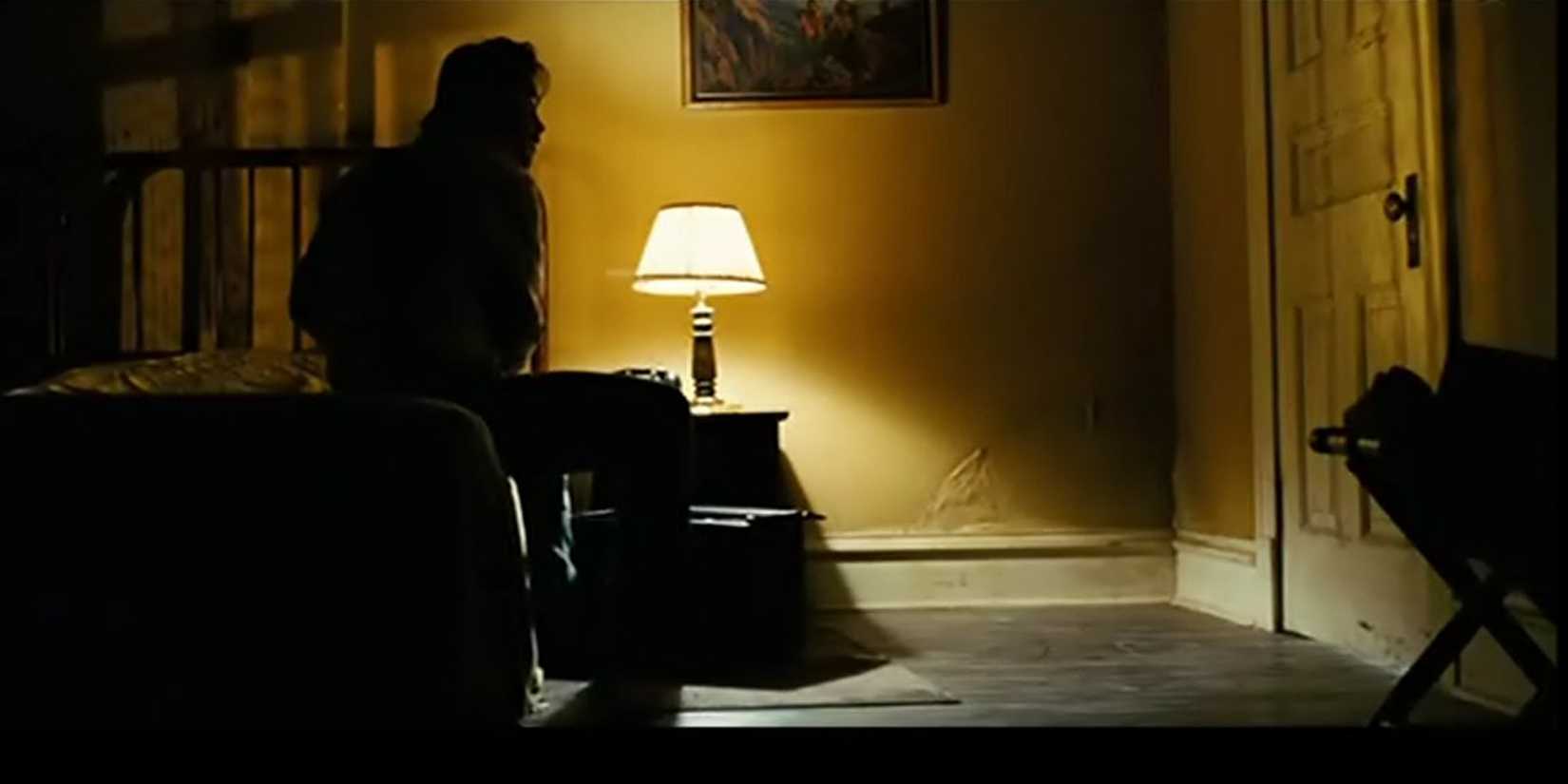 man pointing gun at door in dimly lit motel room