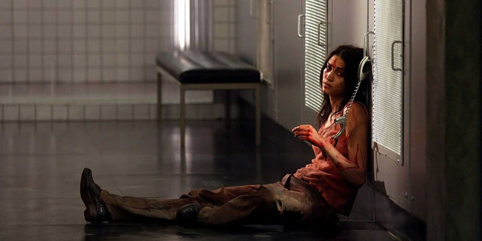 A girl sitting on the floor, getting loose from handcuffs attached to a cabinet