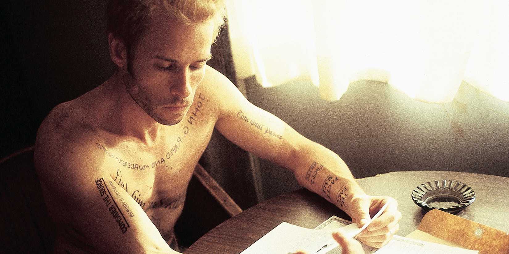 Guy Pearce as Leonard Shelby sitting shirtless while looking at evidence in Memento