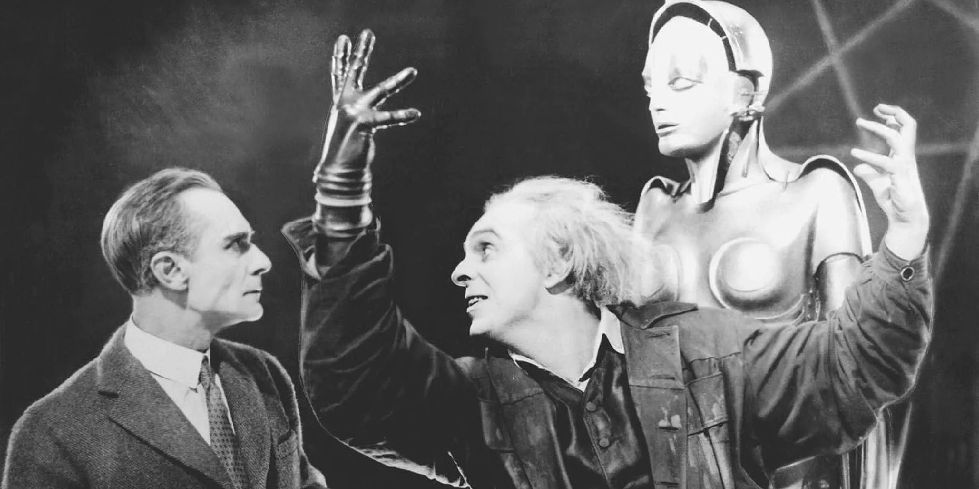One man stares at a robot while the other holds his hands in the air in the silent film Metropolis