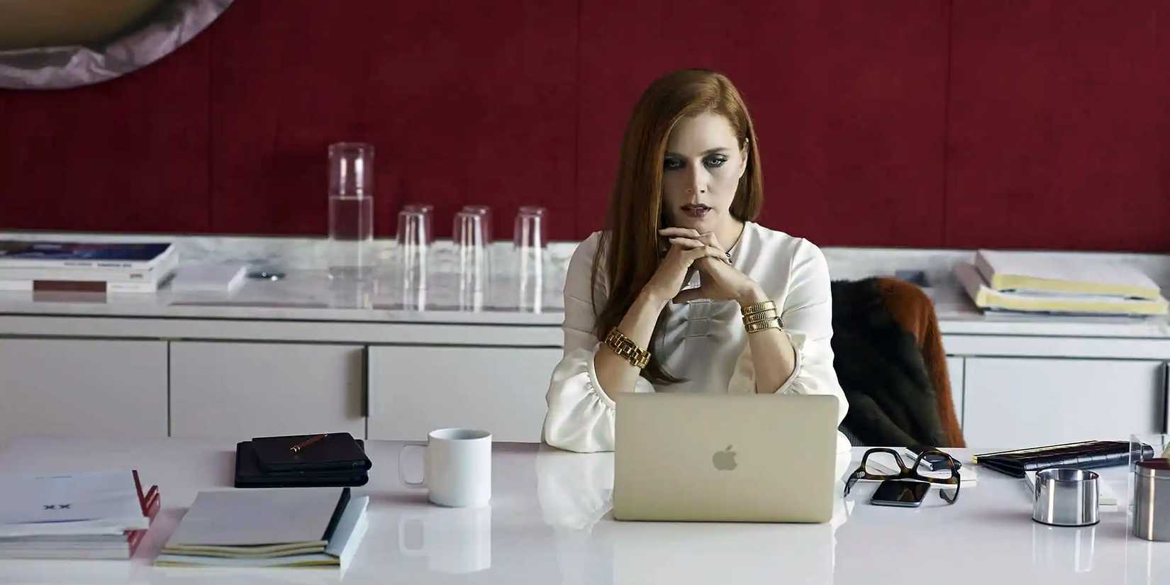 Amy Adams sits at a desk and looks at a laptop in Nocturnal Animals