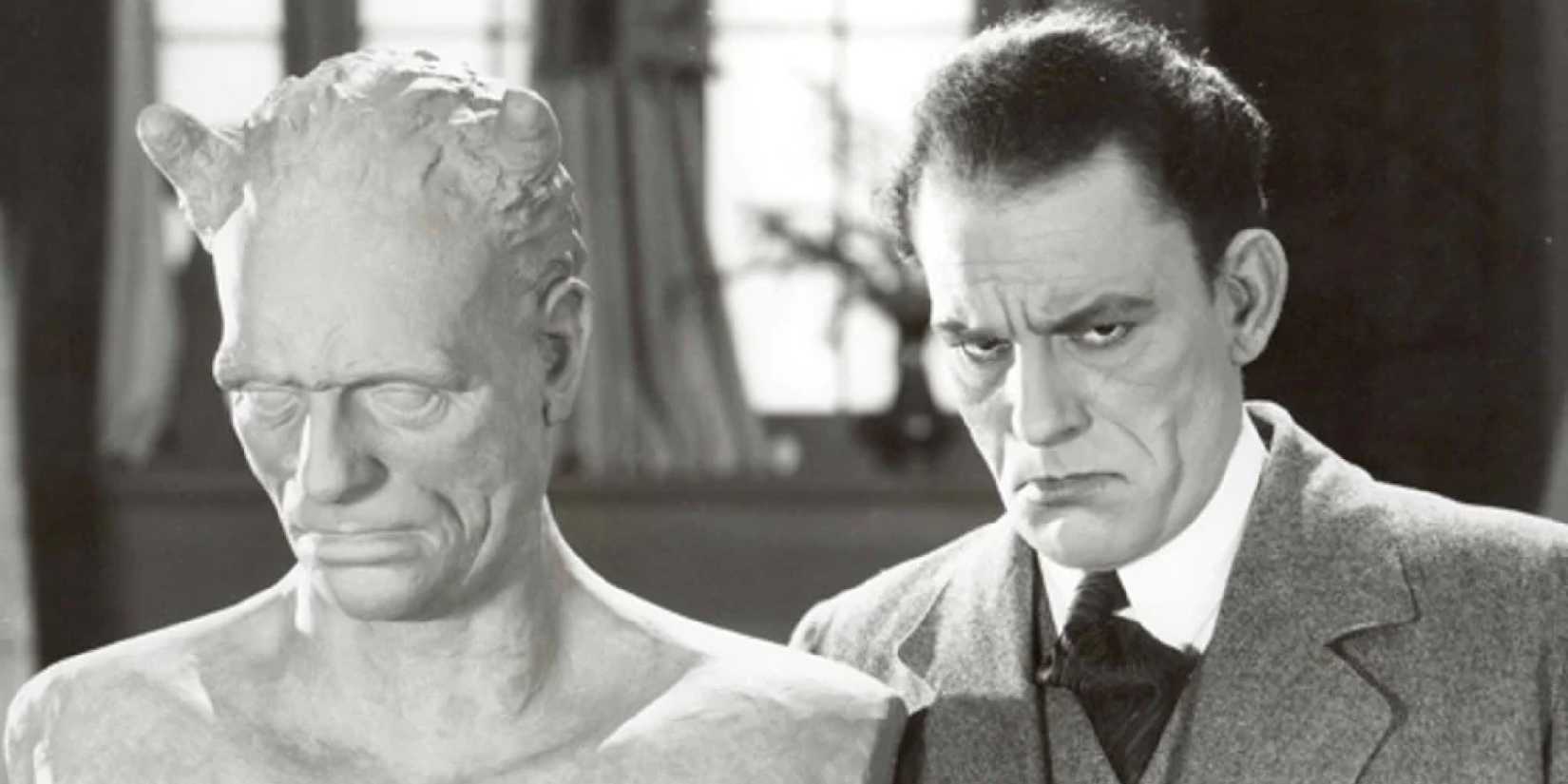 Lon Chaney in The Penalty, standing next to a bust, looking sternly ahead
