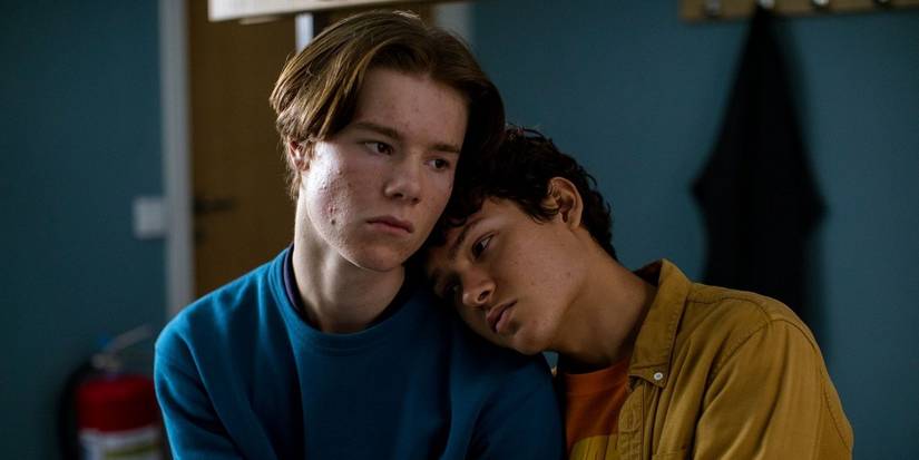 Two teenagers look sad and lean on each other, sitting alone in a room in 'Young Royals.'
